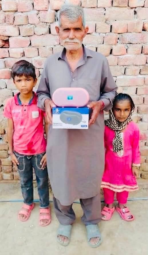An elderly man with his grandchildren holding an Audio Bible device