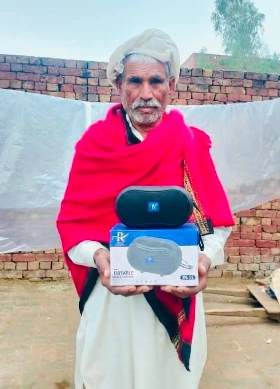 A smiling elderly woman receiving an Audio Bible device in her village
