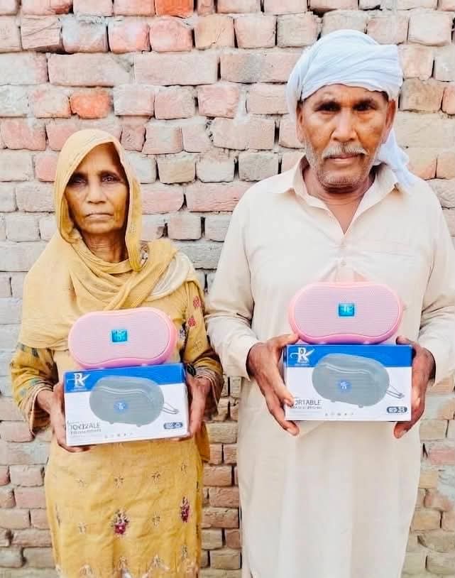 Two elderly women in a village courtyard with their Audio Bible players