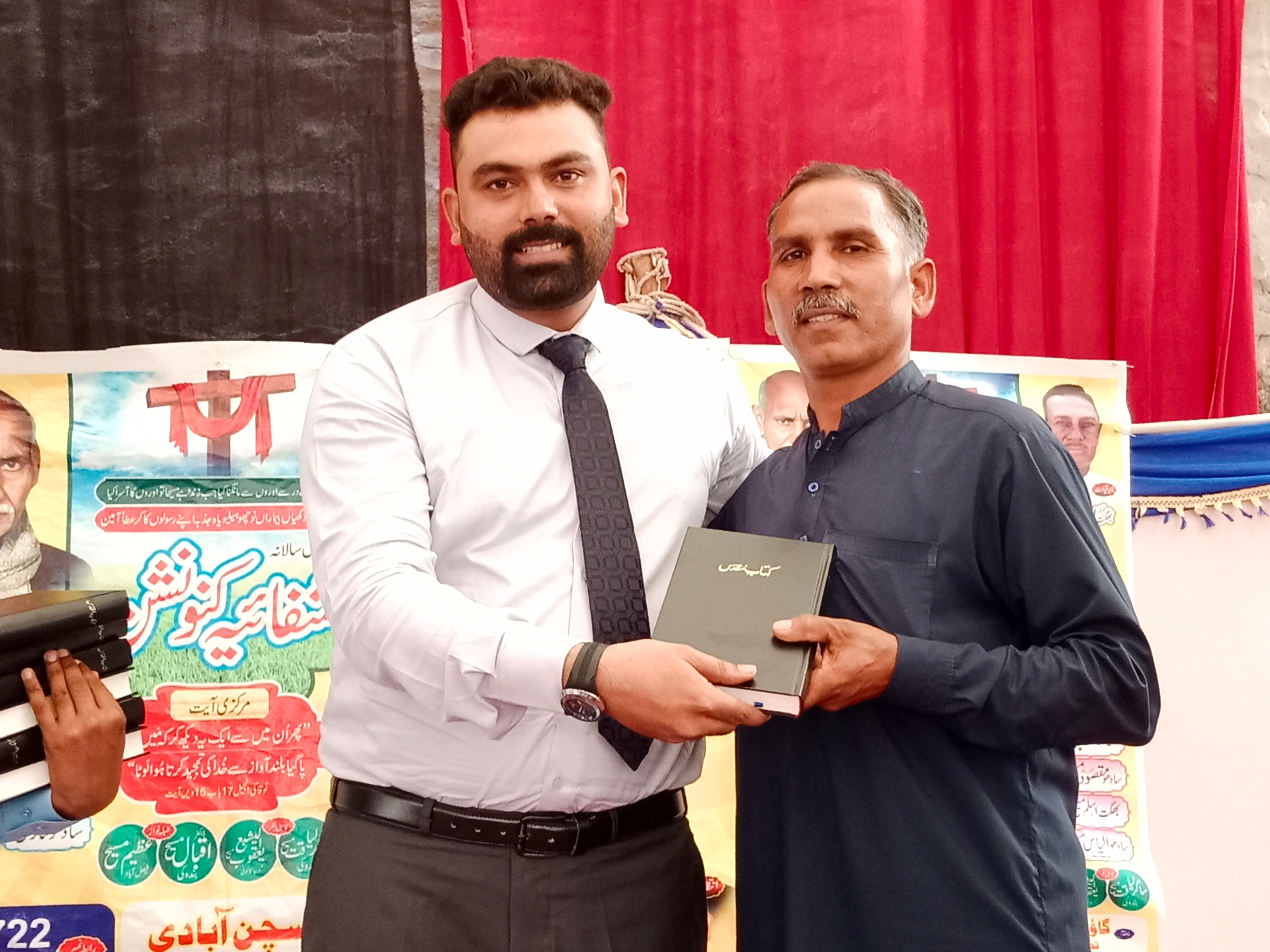 Pastor Shahzad distributing an Urdu Bible at a convention