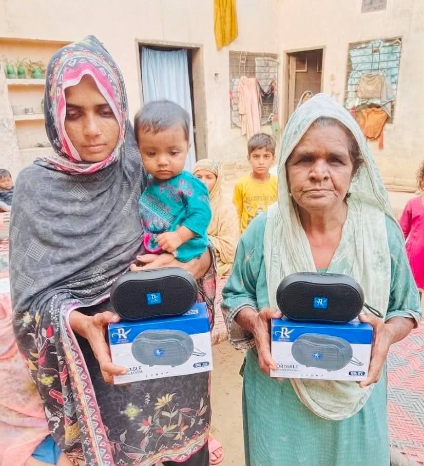 An elderly man in a red shawl holding his Audio Bible player