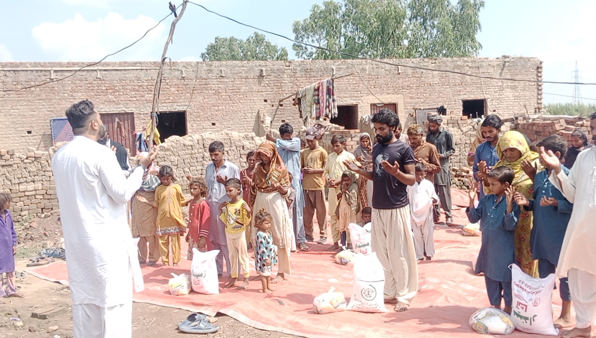 Men, women and children of a brick kiln village lifting their hands in prayer during a flood relief distribution
